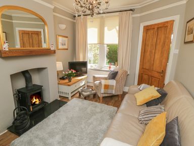 A living room with a fireplace sofa armchair television and a window at Arden House Whitby