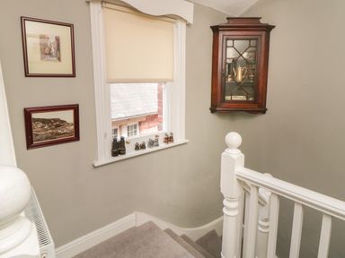 A stairway with a window and small collectibles on the windowsill and pictures on the wall at Arden House in Whitby
