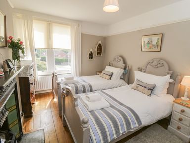 A bedroom with two single beds a window a chest of drawers and a fireplace at Arden House Whitby