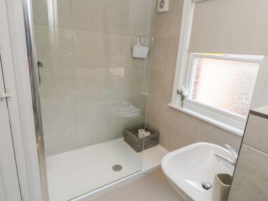 A bathroom with a shower enclosure a window and a sink at Arden House Whitby