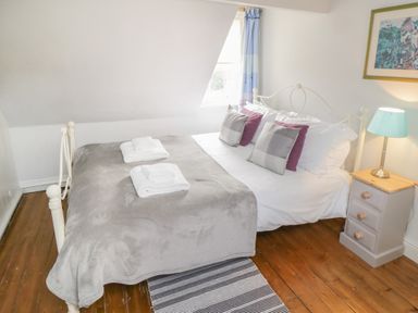 A bedroom with a bed a side table with a lamp and a framed picture on the wall at Arden House Whitby