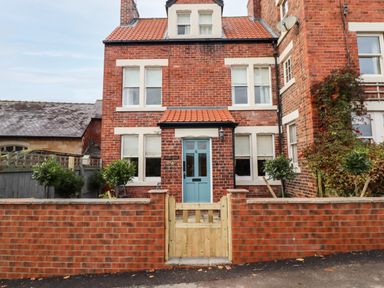 A brick house with a blue front door and a small wooden gate at Arden House in Whitby