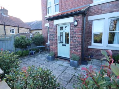 A paved front garden with chairs a table and plants outside a brick house at Arden House in Whitby