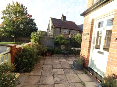 A small paved front garden area with plants chairs and a table outside a house at Arden House in Whitby