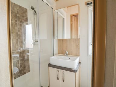 A bathroom with a shower enclosure a sink with cabinet and a mirror at The Hideaway in Cockermouth