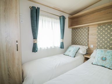 A bedroom with two single beds blue curtains and patterned cushions at The Hideaway in Cockermouth