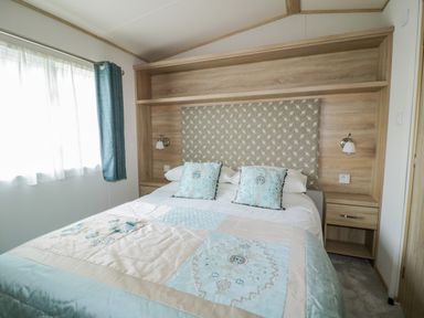 A bedroom with a bed and blue and beige bedding next to a window with blue curtains at The Hideaway in Cockermouth