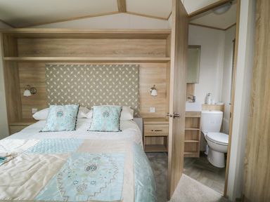 A bedroom with a double bed and a door leading to a bathroom at The Hideaway in Cockermouth