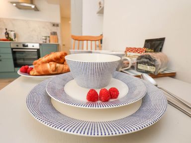 A kitchen table set with blue dotted plates cups croissants and raspberries at The Riddle in Whitby