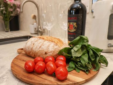 A kitchen countertop with bread cherry tomatoes basil wine bottle and two wine glasses at The Riddle in Whitby