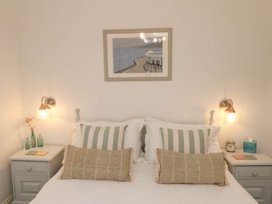 A bedroom with a bed flanked by two nightstands each with lamps and decor at The Riddle in Whitby