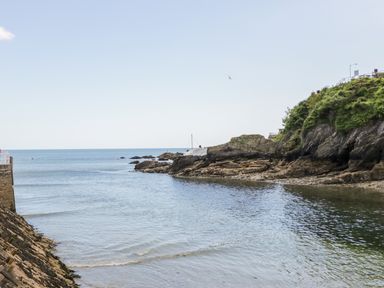 A coastal scene with rocky cliffs and calm sea water at 6 Valley View in Lanreath