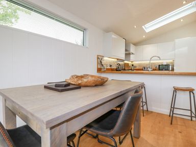 A kitchen and dining area with a wooden table chairs stools and kitchen appliances at 6 Valley View in Lanreath