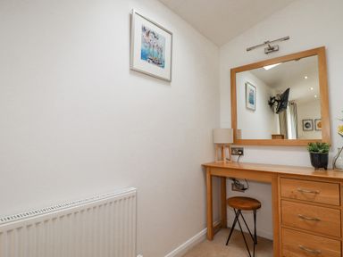 A wooden vanity table with a mirror stool lamp and potted plants in a small room at 6 Valley View in Lanreath