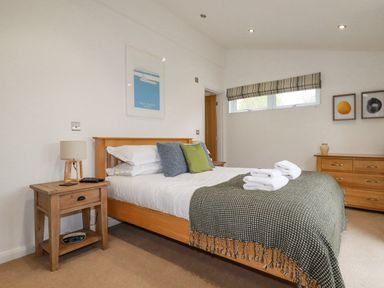 A bedroom with a wooden bed and bedside table with lamp and alarm clock at 6 Valley View in Lanreath