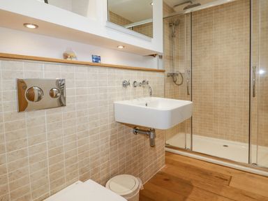 A bathroom with a wall-mounted sink a shower enclosure and a toilet at 6 Valley View in Lanreath