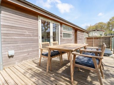 A wooden deck with a table and four chairs outside a wooden building at 6 Valley View in Lanreath