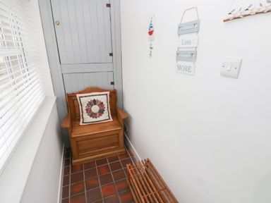 A small hallway with a wooden bench and a cushion beside a window and a grey door at Ty'r Winllan in Newport Pembrokeshire