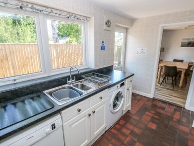 A kitchen with a double sink dishwasher washing machine and view into a dining room at Ty'r Winllan in Newport Pembrokeshire