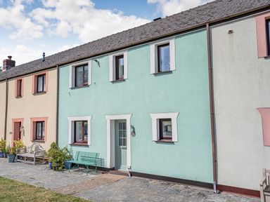A row of terraced houses with benches and potted plants outside at Granary Cottage in Pembroke