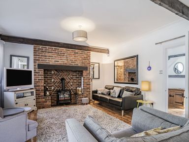 A living room with a brick fireplace a black sofa and a gray armchair at Granary Cottage in Pembroke