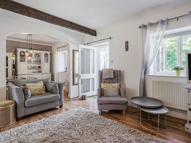 A living room with an armchair sofa dining table and cabinet at Granary Cottage in Pembroke