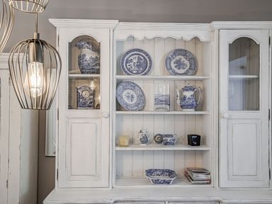 A white cabinet with blue and white china plates cups and pitchers at Granary Cottage in Pembroke