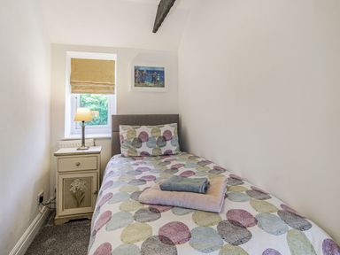 A small bedroom with a single bed next to a window and a bedside table with a lamp at Granary Cottage in Pembroke