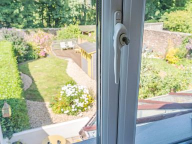 A view through a window showing a garden with grass paths flowers and outdoor furniture at Granary Cottage in Pembroke