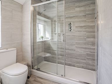 A bathroom with a toilet and a glass-enclosed shower at Granary Cottage in Pembroke