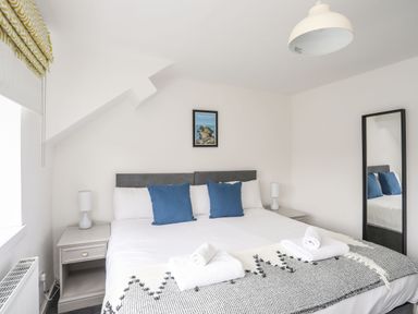 A bedroom with a double bed blue pillows and bedside tables with lamps at Gorwel in Moelfre