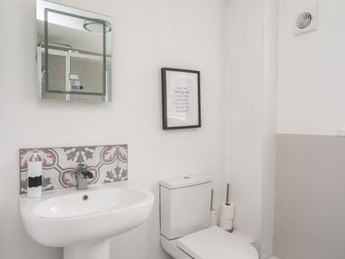 A bathroom with a sink, toilet, mirror, and framed sign on the wall at Gorwel in Moelfre