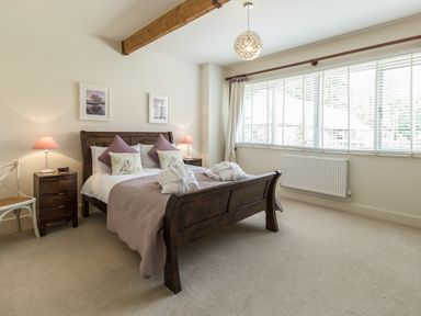 A bedroom with a wooden bed and nightstands with lamps at Sawmill Cottage in Belford near Bamburgh