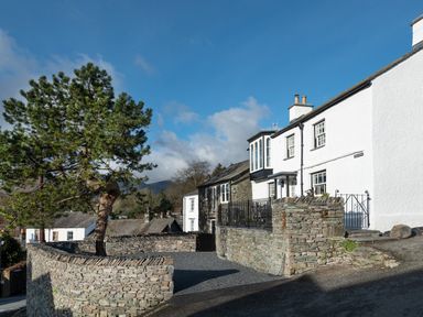 Stone wall and tree outside white houses on a street at Prospect House in Ambleside