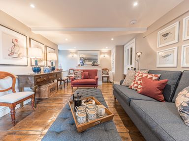 A living room with a blue sofa and red armchair wooden furniture and bird artwork at Prospect House in Ambleside