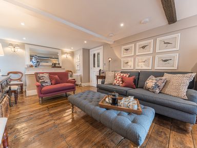 A living room with a gray sofa a red armchair wooden floor and framed bird pictures on the wall at Prospect House in Ambleside