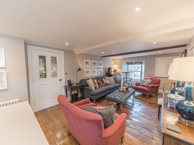 A living room with red armchairs blue sofa coffee table wooden floor and desk at Prospect House in Ambleside