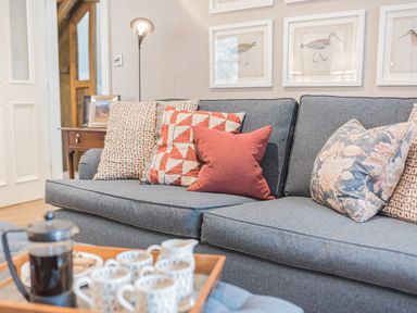 A grey sofa with patterned cushions and a tray with coffee cups and a French press in a living room at Prospect House in Ambleside