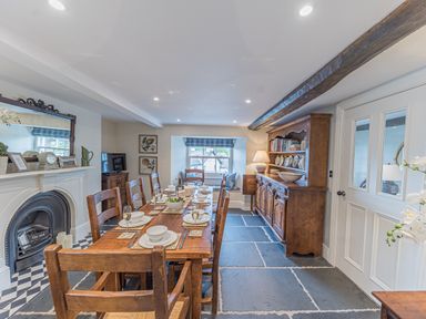 A dining room with a wooden table and chairs a fireplace and a wooden cabinet at Prospect House in Ambleside