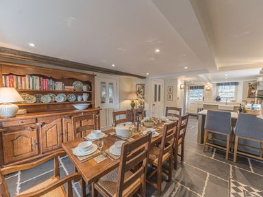 A dining area with wooden table and chairs set with dishes and glasses next to a wooden cabinet with books and plates at Prospect House in Ambleside