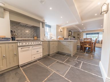 A kitchen with gas stove and cabinetry connected to a dining area with wooden table and chairs at Prospect House Ambleside