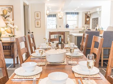 A dining table set with bowls plates glasses and a white pot in a kitchen with wooden chairs at Prospect House in Ambleside