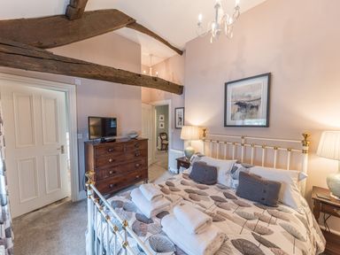 A bedroom with a bed folded towels on the bed bedside tables with lamps a wooden chest of drawers and exposed wooden beams at Prospect House in Ambleside