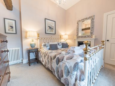 A bedroom with a metal bed frame bedside tables lamps a chest of drawers and a mirror at Prospect House in Ambleside