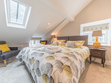 A bedroom with a double bed armchairs bedside tables lamps and skylight windows at Prospect House in Ambleside