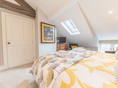 A bedroom with a bed with yellow and gray bedding a wooden chest of drawers and a skylight window at Prospect House in Ambleside