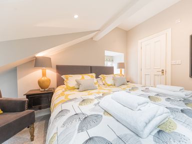A bedroom with twin beds with folded towels on them bedside lamps and an armchair at Prospect House in Ambleside