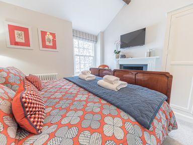 A bedroom with a patterned bedspread two framed pictures and a wall mounted television at Prospect House in Ambleside