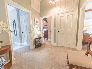 A hallway with beige carpet multiple white doors a wooden chair a side table with lamp and vases at Prospect House in Ambleside