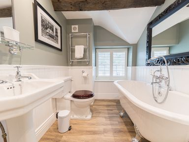 A bathroom with a clawfoot bathtub a toilet with a wooden seat and a pedestal sink at Prospect House in Ambleside